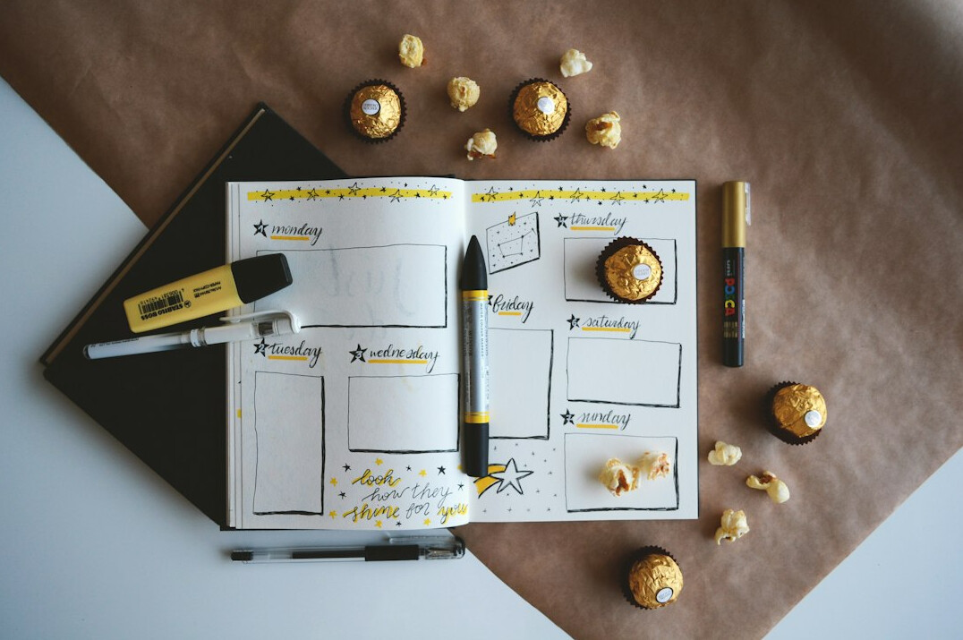 Open weekly planner with colorful pens on a desk