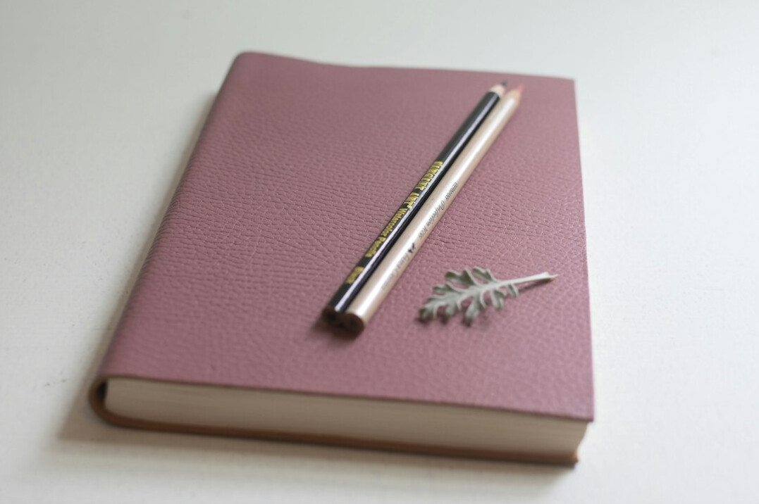 Notebook with a pen resting on top of a closed journal